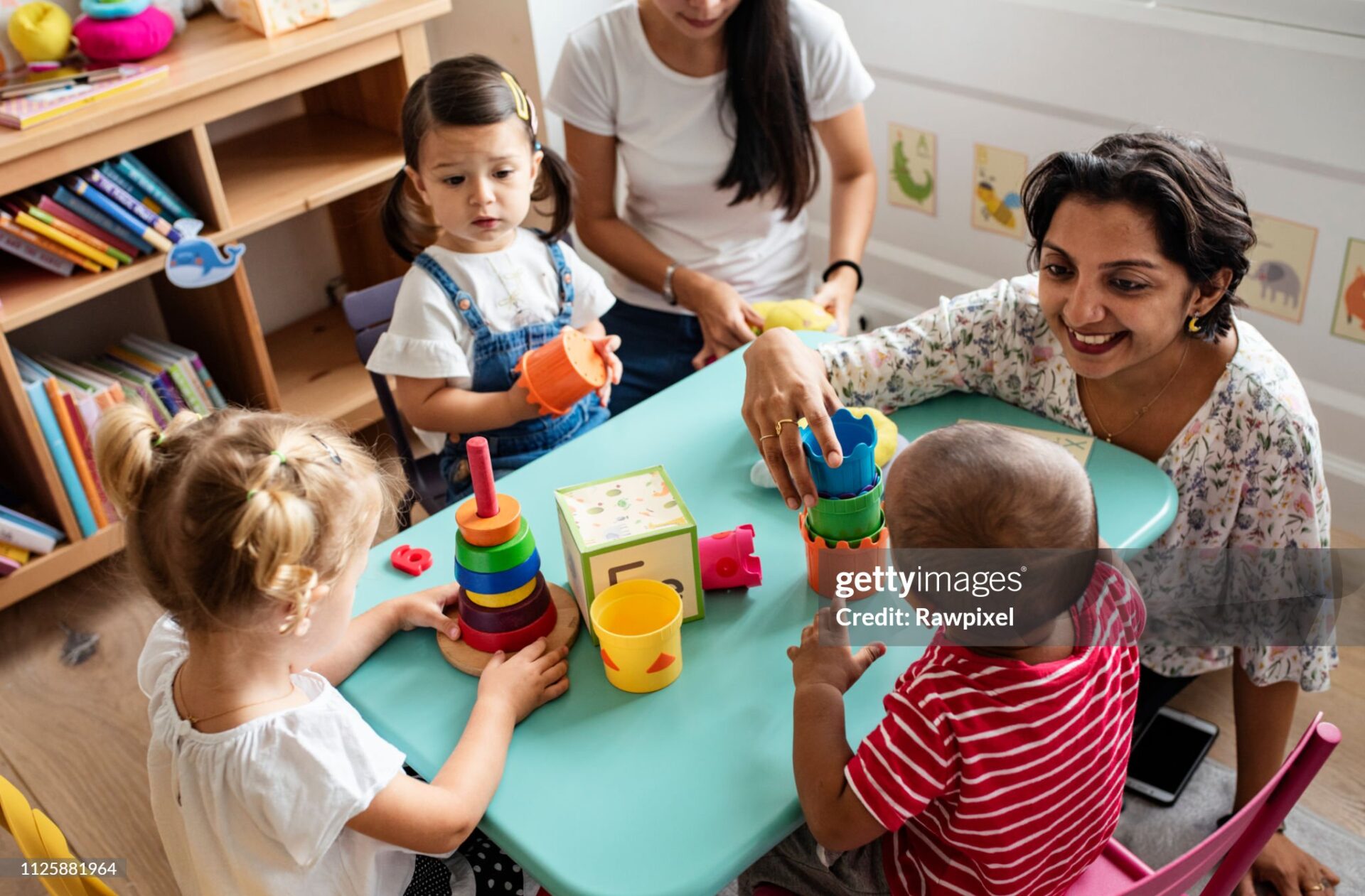 Nursery children playing with teacher in the classroom