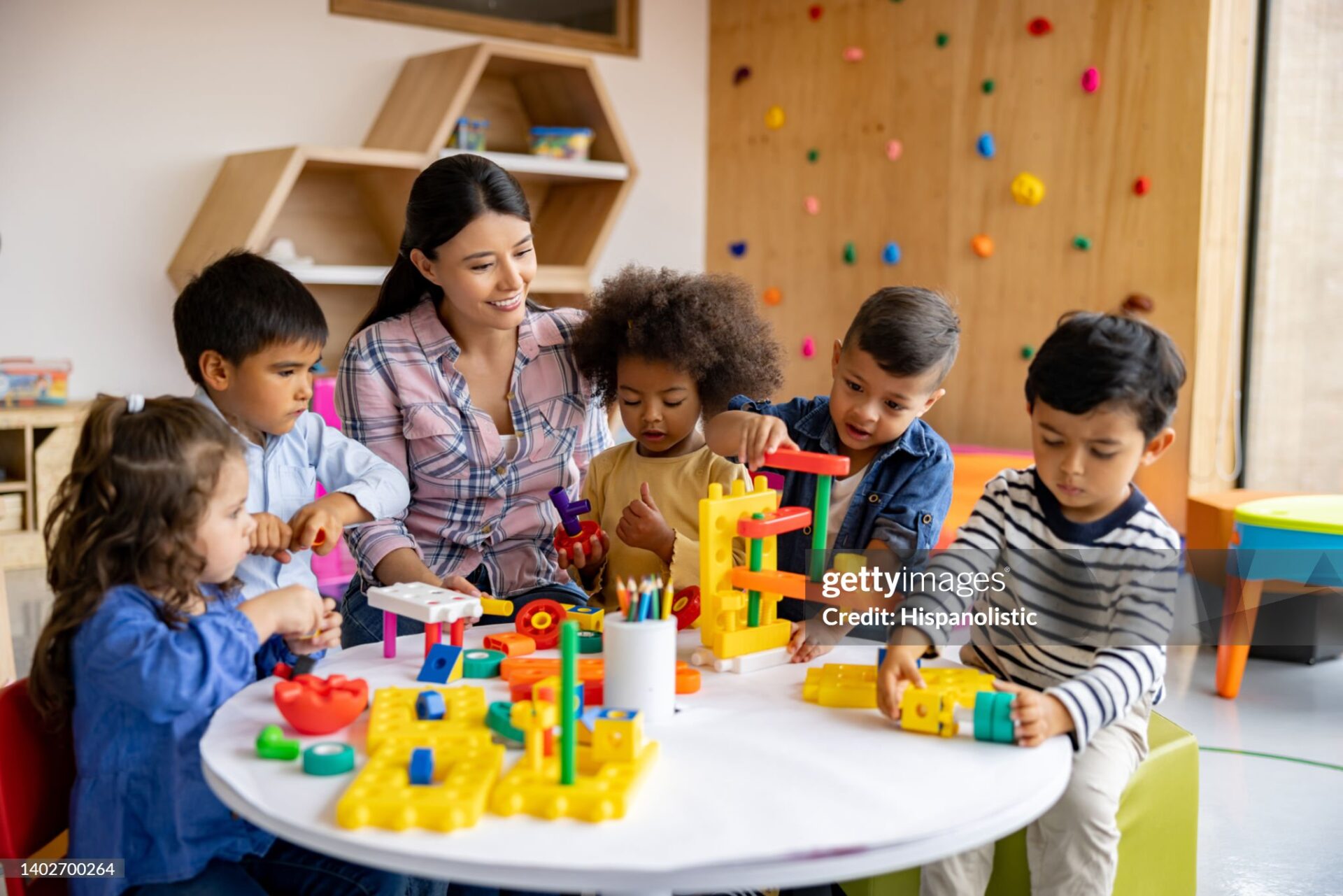 Happy Latin American teacher with a group of elementary students playing with toy blocks