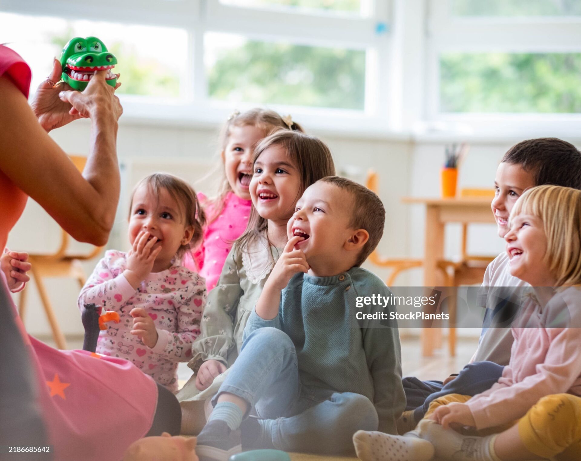 the teacher entertains the children in the kindergarten, the children are happy and enjoying themselves